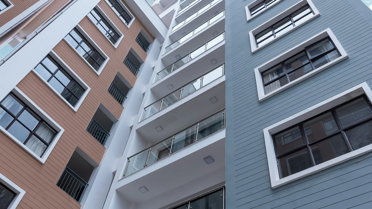 Prédios residenciais vistos de baixo para cima, com o céu azul ao fundo.