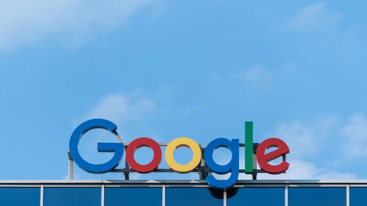 Logotipo do Google em letras grandes no alto de um prédio, contra o céu azul.