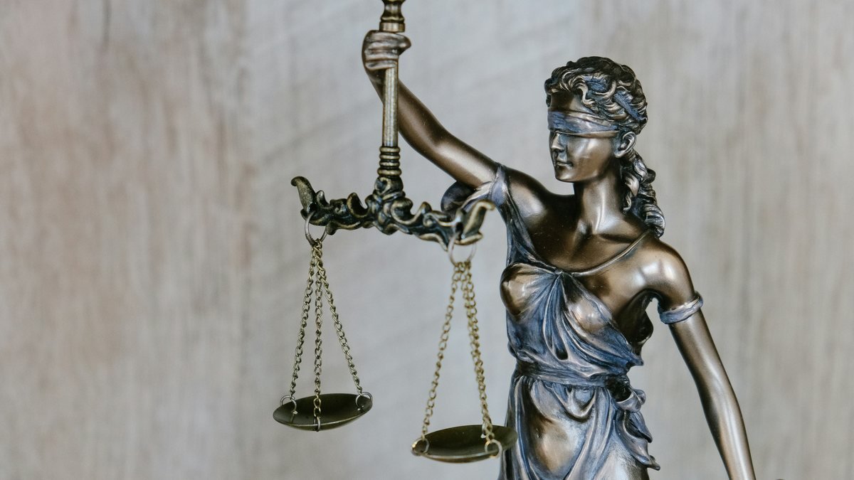 Estátua da justiça segurando uma balança, em close.