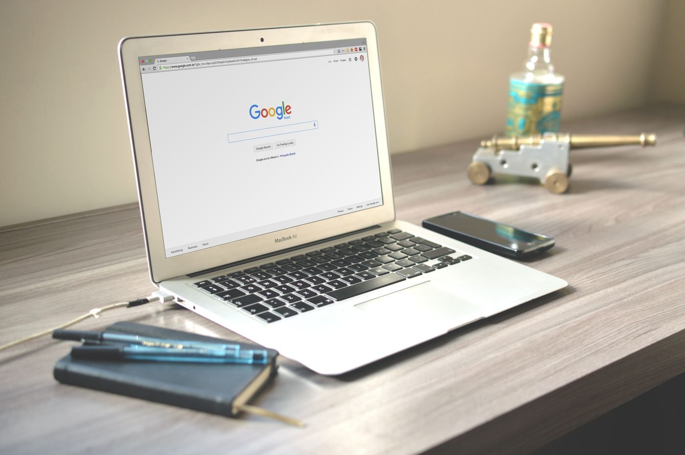 Notebook aberto na página de busca do Google, sobre uma escrivaninha de madeira.