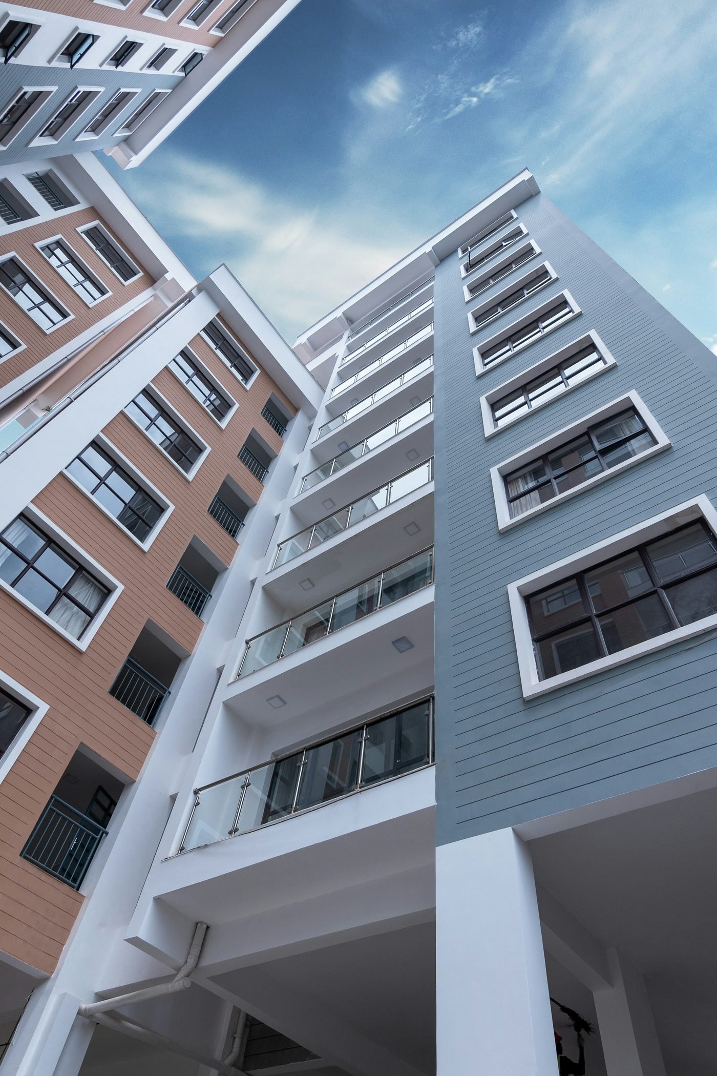 Prédios residenciais vistos de baixo para cima, com o céu azul ao fundo.