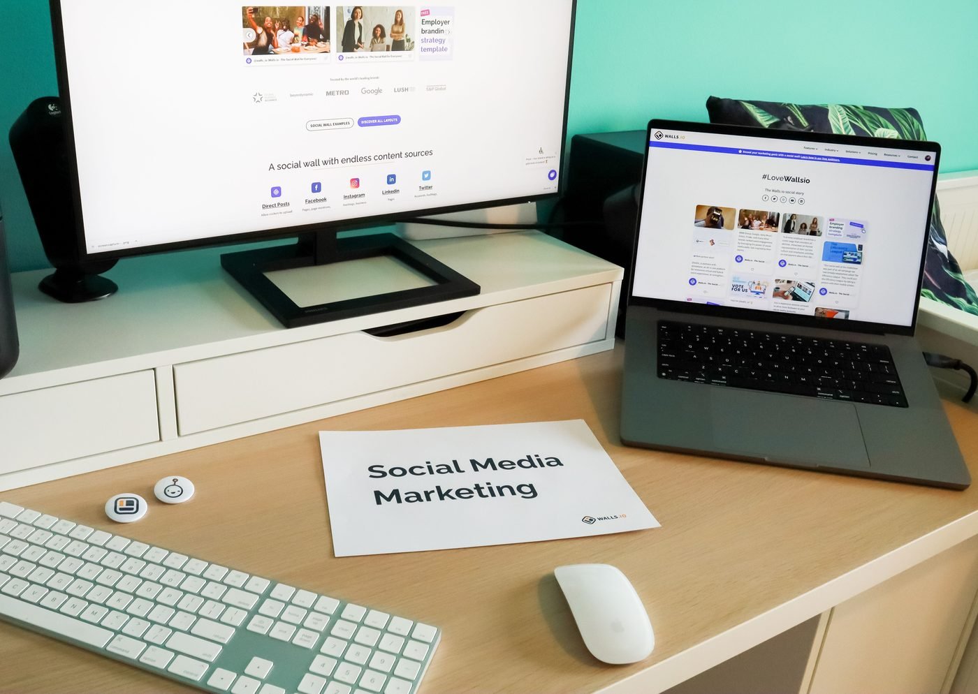 Mesa de trabalho com dois monitores abertos em redes sociais e uma folha escrita "Social Media Marketing".